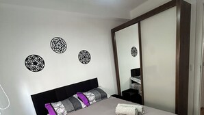 A neatly made bed with a headboard, a bedside table, a nightstand, and a mirror. - Apto Allianz Metrô Barra Funda (Várzea da Barra Funda São Paulo)