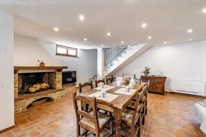 Ein Essbereich mit Kamin, einem Holztisch, Stühlen und einer Treppe.