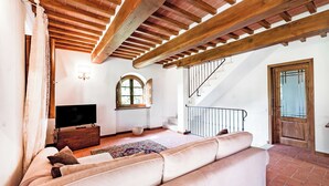 Ein Wohnzimmer mit einer Couch, einem Fernseher, einer Holzbalkendecke und einer Treppe.