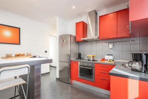 A modern kitchen with red cabinets, stainless steel appliances, and a tiled backsplash.