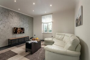 A modern living room with a sectional sofa, a coffee table, a bench, and a television.