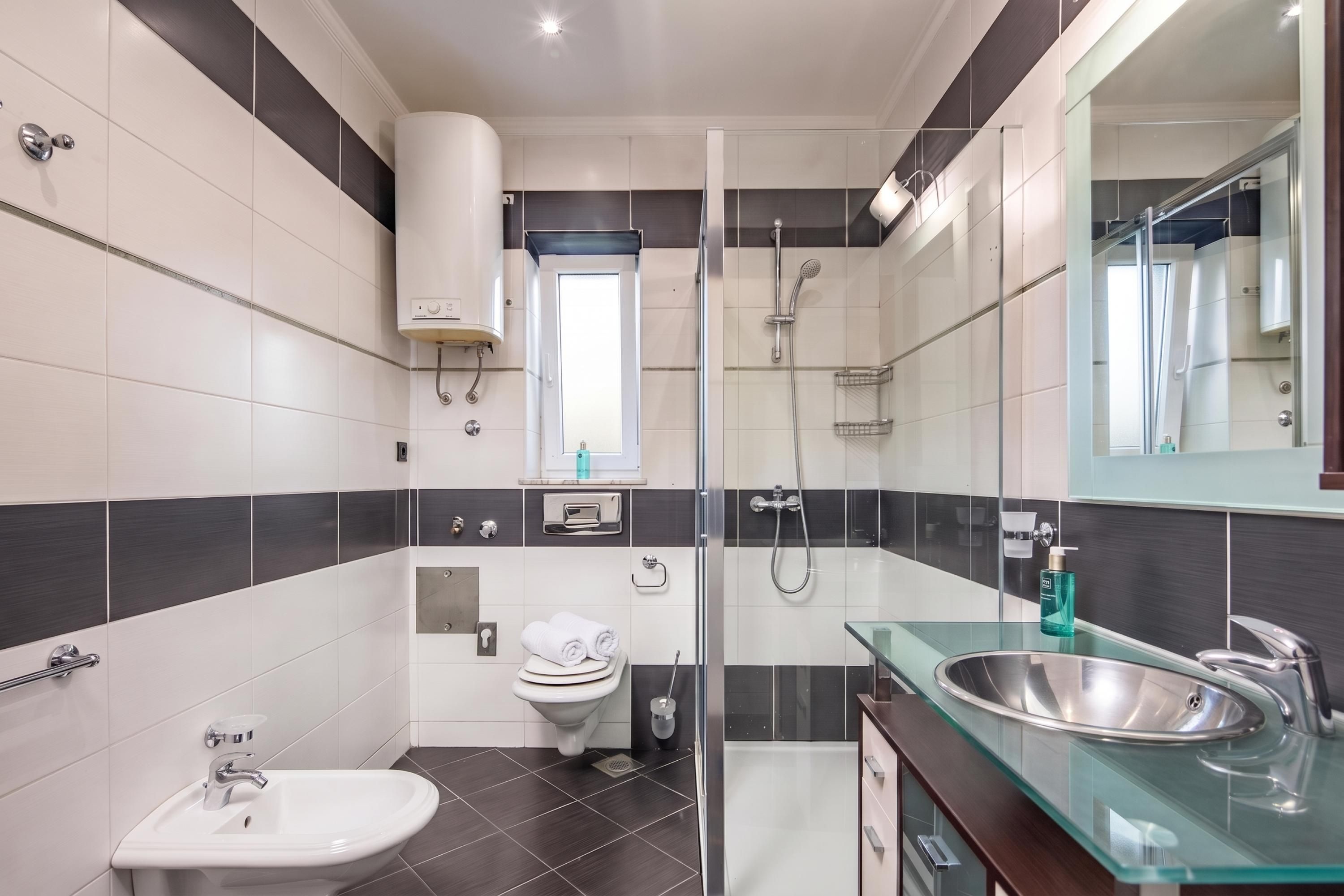A modern bathroom with a glass shower enclosure, a white sink, and a toilet.
