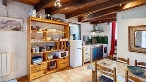 Una cocina con estantes de madera, una mesa de comedor y un refrigerador.