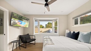 Une chambre avec un lit, une chaise, une télévision et une fenêtre donnant sur une piscine.