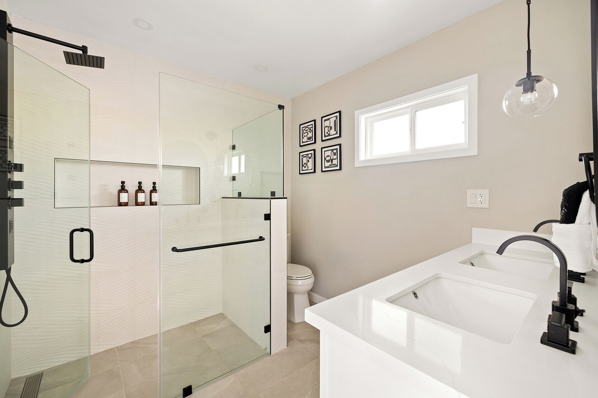 A modern bathroom with a glass-enclosed shower, a white sink, and a toilet.