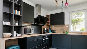 Una cocina moderna con armarios negros, microondas, horno y pileta.