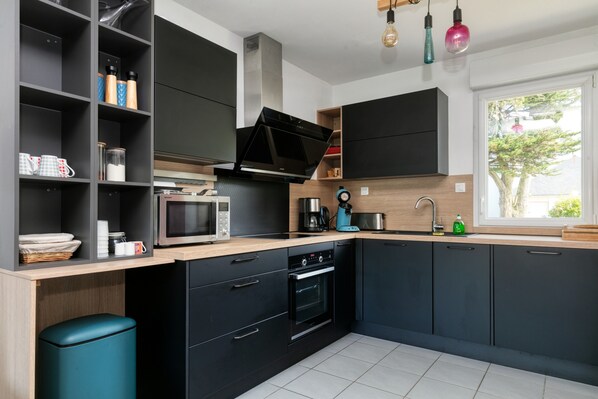 A modern kitchen with black cabinets, a microwave, an oven, and a sink.
