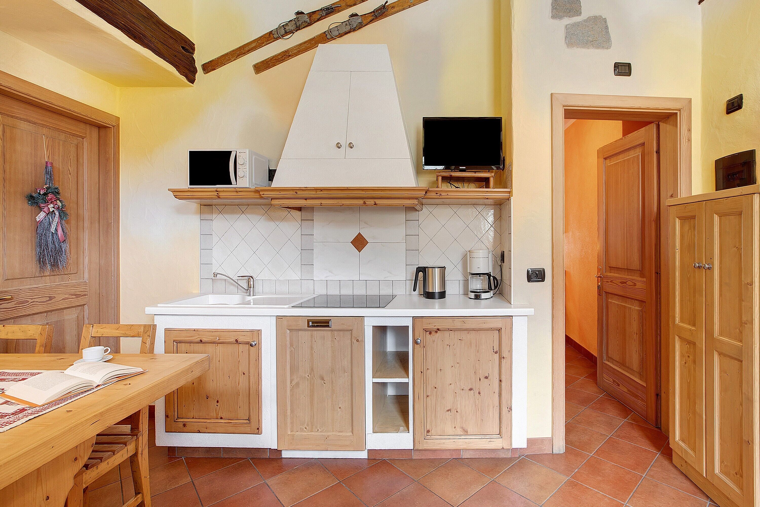 A kitchen with wooden cabinets, a white countertop, a microwave, and a television.