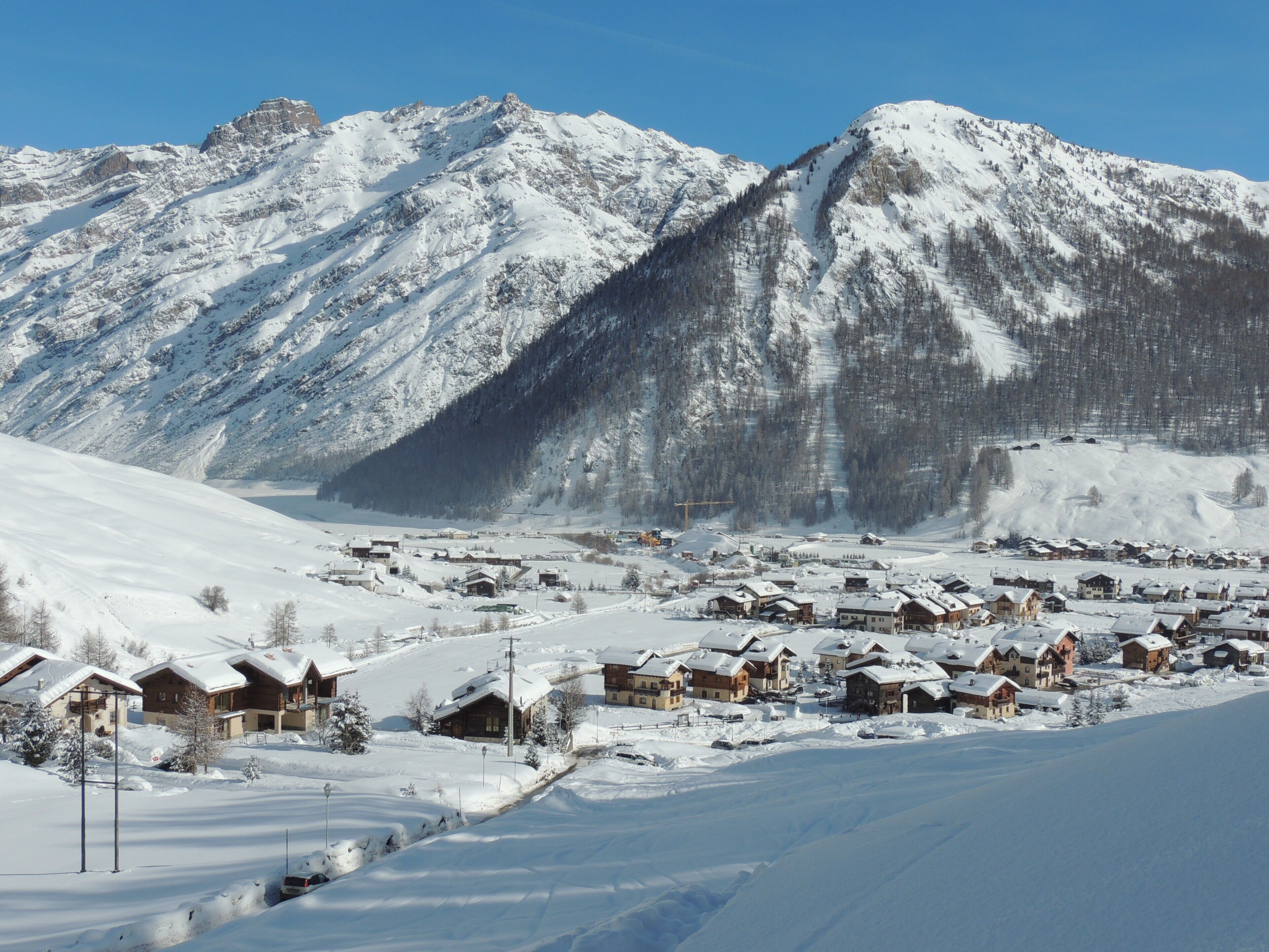 A snow-covered mountain village with wooden houses and a clear sky.