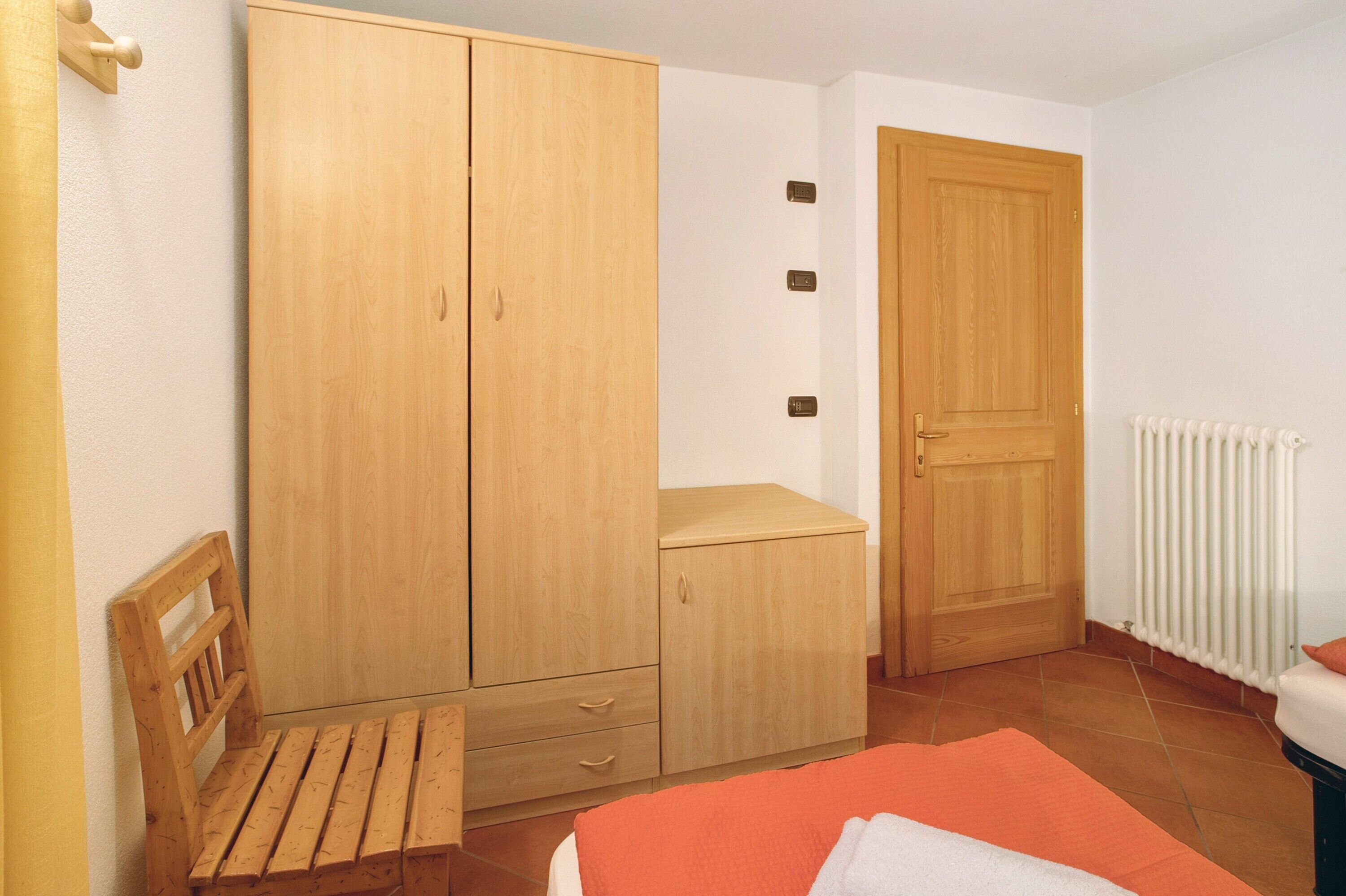 Ein Schlafzimmer mit einem Holfterschrank, einer kleinen Bank, einem Bett und einer Heizung.