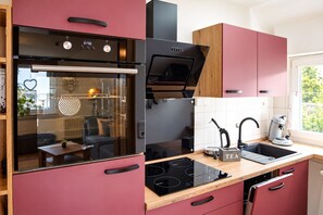 Une cuisine moderne équipée d’un four encastré, d’une plaque de cuisson et d’une machine à café.