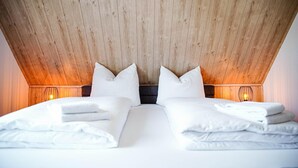 A double bed with white linens and pillows, wooden ceiling, and two bedside lamps. - Fewo Renauweg - Gemütliche Ferienwohnung in Ruhiger Lage (Winterberg)