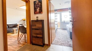 A hallway leading to a bedroom with a bed, a nightstand, and a window with a heart-shaped decoration. - Fewo Renauweg - Gemütliche Ferienwohnung in Ruhiger Lage (Winterberg)