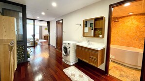 A modern bathroom with a washing machine, a sink, and a mirror.