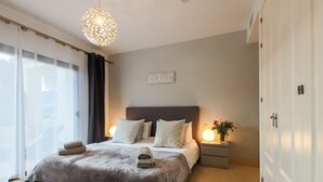Un dormitorio con cama, mesita de noche, lámpara de pared y una puerta.
