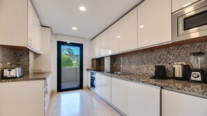 Eine moderne Küche mit weißen Schränken, Granitarbeitsplatten, einem Backofen und einer Kaffeemaschine.