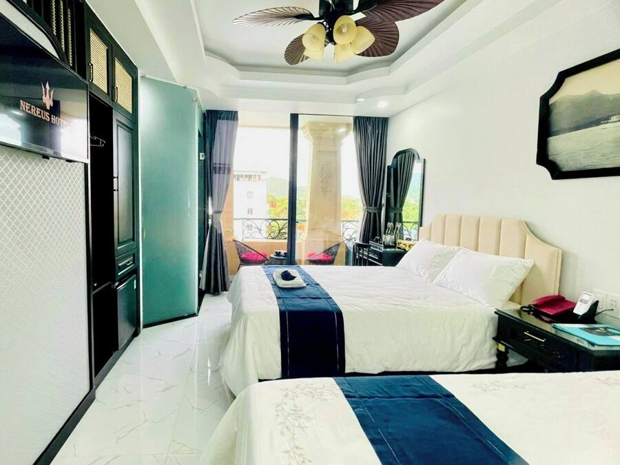 A hotel room with a bed, a desk with a phone, and a balcony with a view.