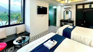 Ein Hotelzimmer mit zwei Betten, einem Fernseher, einem Schreibtisch und einem Badezimmer.