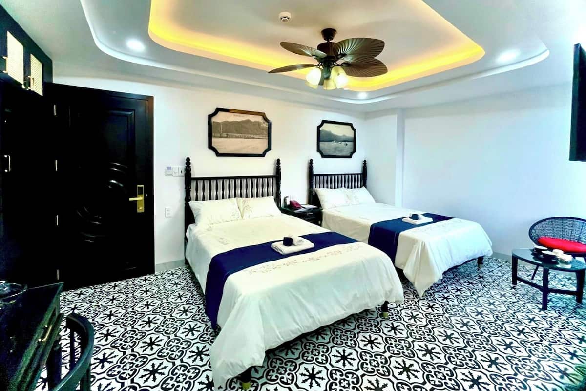 Ein Hotelzimmer mit zwei Betten, einem Deckenventilator und einem gemusterten Boden.