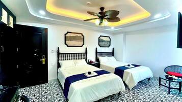 Une chambre d’hôtel avec deux lits, un ventilateur de plafond et un revêtement de sol à motifs.