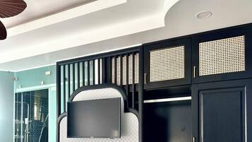 A modern hotel room with a bed, a built-in TV, a wardrobe, and a small refrigerator.