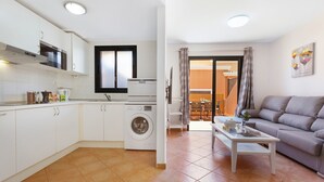 Un espacio habitable compacto con cocina, lavadora, sofá y mesa de comedor.