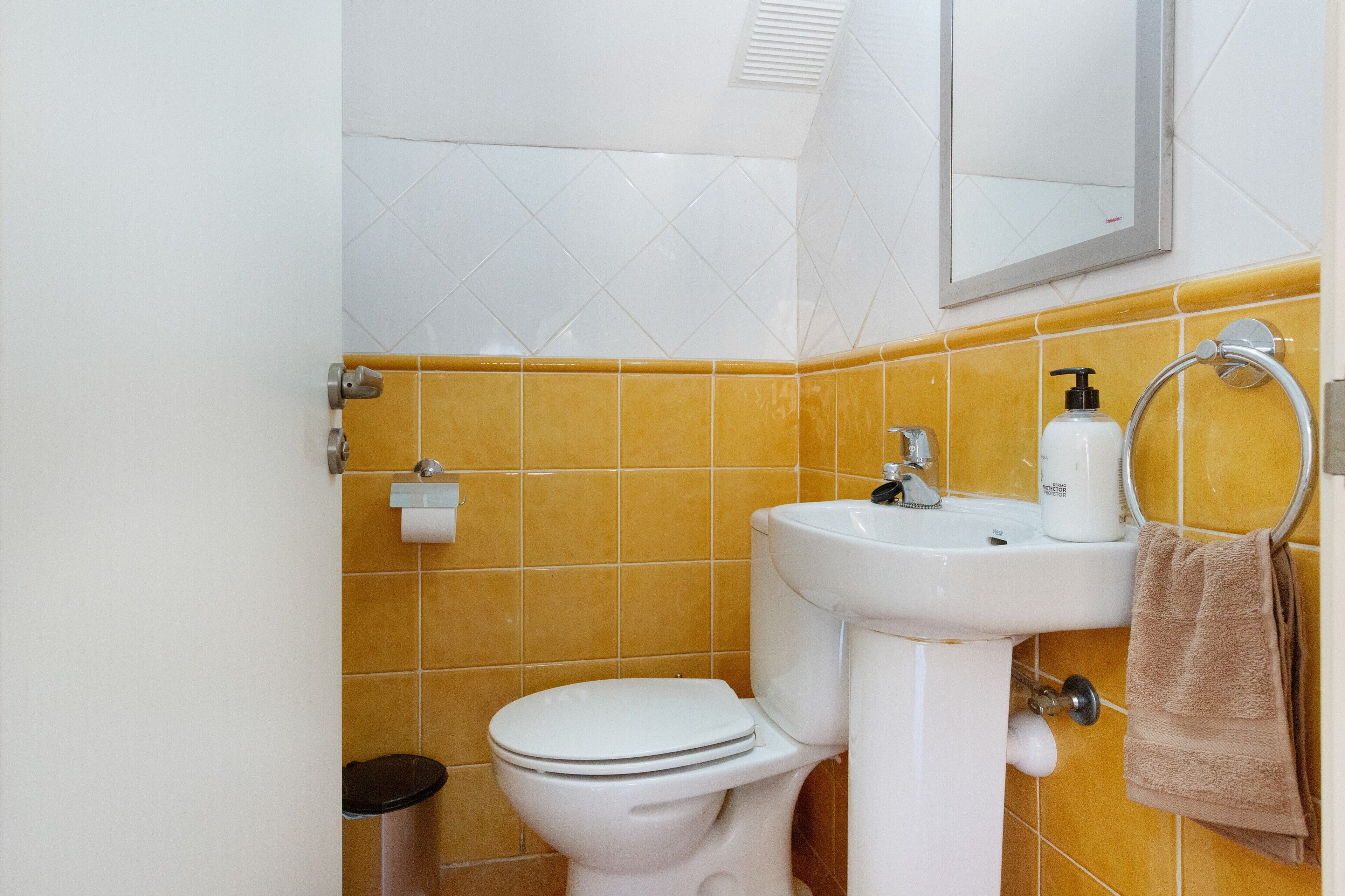 A bathroom with a toilet, sink, and towel rack.