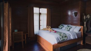 Un dormitorio tipo cabaña de madera con una cama, una mesita y una ventana con cortinas.