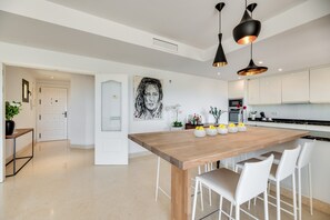 Una cucina moderna con isola centrale, mobili bianchi e illuminazione a sospensione.