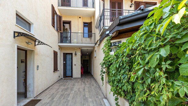 A narrow alleyway with a wooden floor, a door on the left, and a wall with climbing plants. - Apartment 'Verona Fh' with Shared Garden, Wi-Fi and Air Conditioning (Verona)