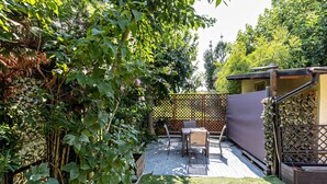 A patio with a table and chairs, surrounded by greenery and a fence. - Apartment 'Verona Fh' with Shared Garden, Wi-Fi and Air Conditioning (Verona)