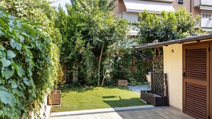 A garden with a wooden deck, a door, and a building in the background. - Apartment 'Verona Fh' with Shared Garden, Wi-Fi and Air Conditioning (Verona)