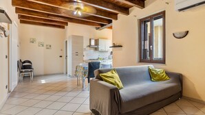 A living room with a sofa, a dining table with chairs, a kitchen area, and a ceiling with exposed beams. - Apartment 'Verona Fh' with Shared Garden, Wi-Fi and Air Conditioning (Verona)