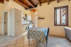Una cucina compatta con elettrodomestici moderni, un tavolo da pranzo con tovaglia a fiori e una finestra con vista sul balcone.