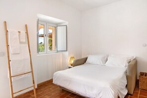 Une chambre à coucher avec un lit, une fenêtre, une table de chevet, une lampe et un porte-serviettes.
