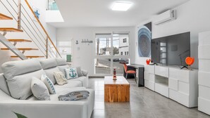 A modern living room with a staircase, a sofa, a coffee table, and a TV stand. - Vacation Apartment 'Sparrow' with Wi-Fi and Air Conditioning (La Santa)