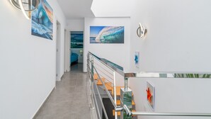 A modern interior with a staircase, wall-mounted artwork, and a metal railing. - Vacation Apartment 'Sparrow' with Wi-Fi and Air Conditioning (La Santa)