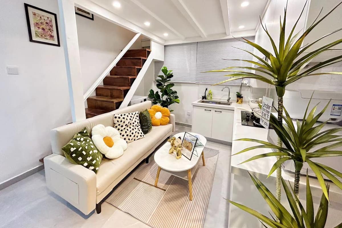 A modern apartment with a living area, kitchen, and staircase.