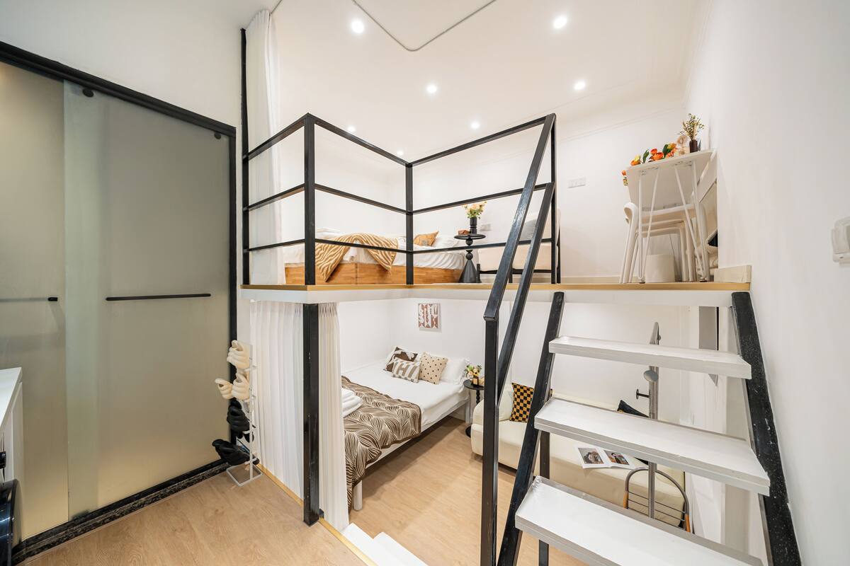 A compact room with a bunk bed, a small desk, and a chair.