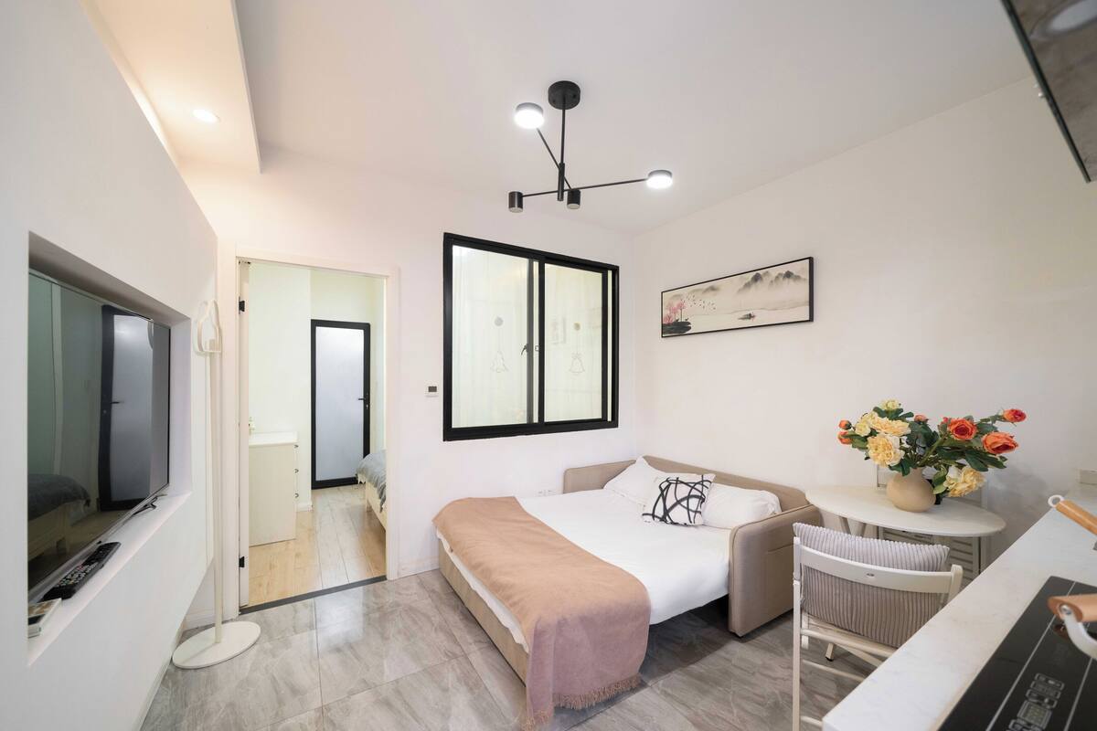 A modern bedroom with a bed, bedside table, and a TV.