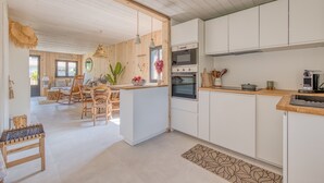 Eine moderne Küche mit weißen Schränken, Holzarbeitsplatten und einem Essbereich mit einem Holztisch und Stühlen.