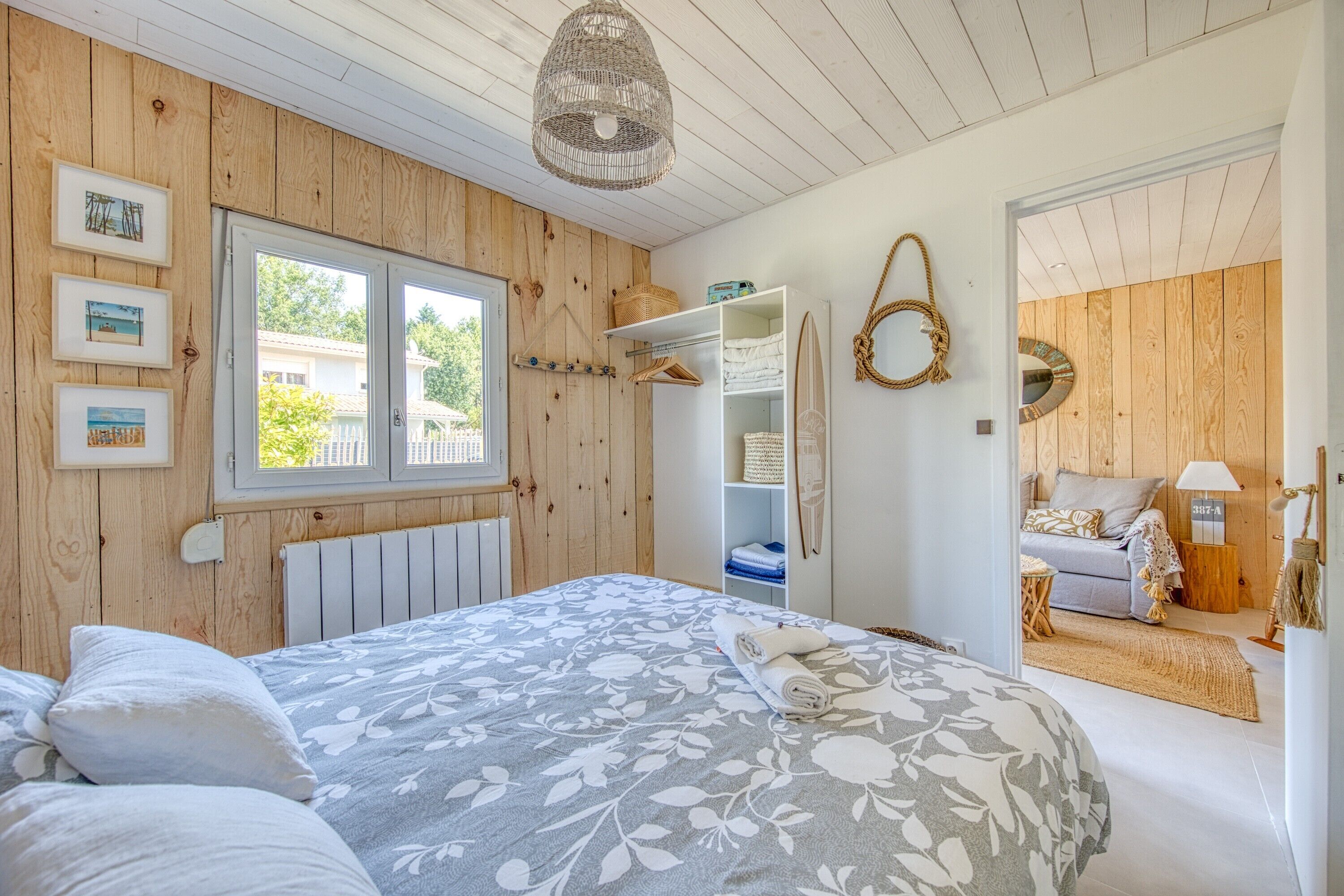 A bedroom with a bed, a window, a wardrobe, and a door leading to another room.