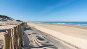 Ein Strand mit einer Holzzahlung und blauem Himmel.