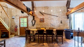 Ein Essbereich mit Steinwand, Holzbalken, einer Holztreppe und einem Feuerlöscher.