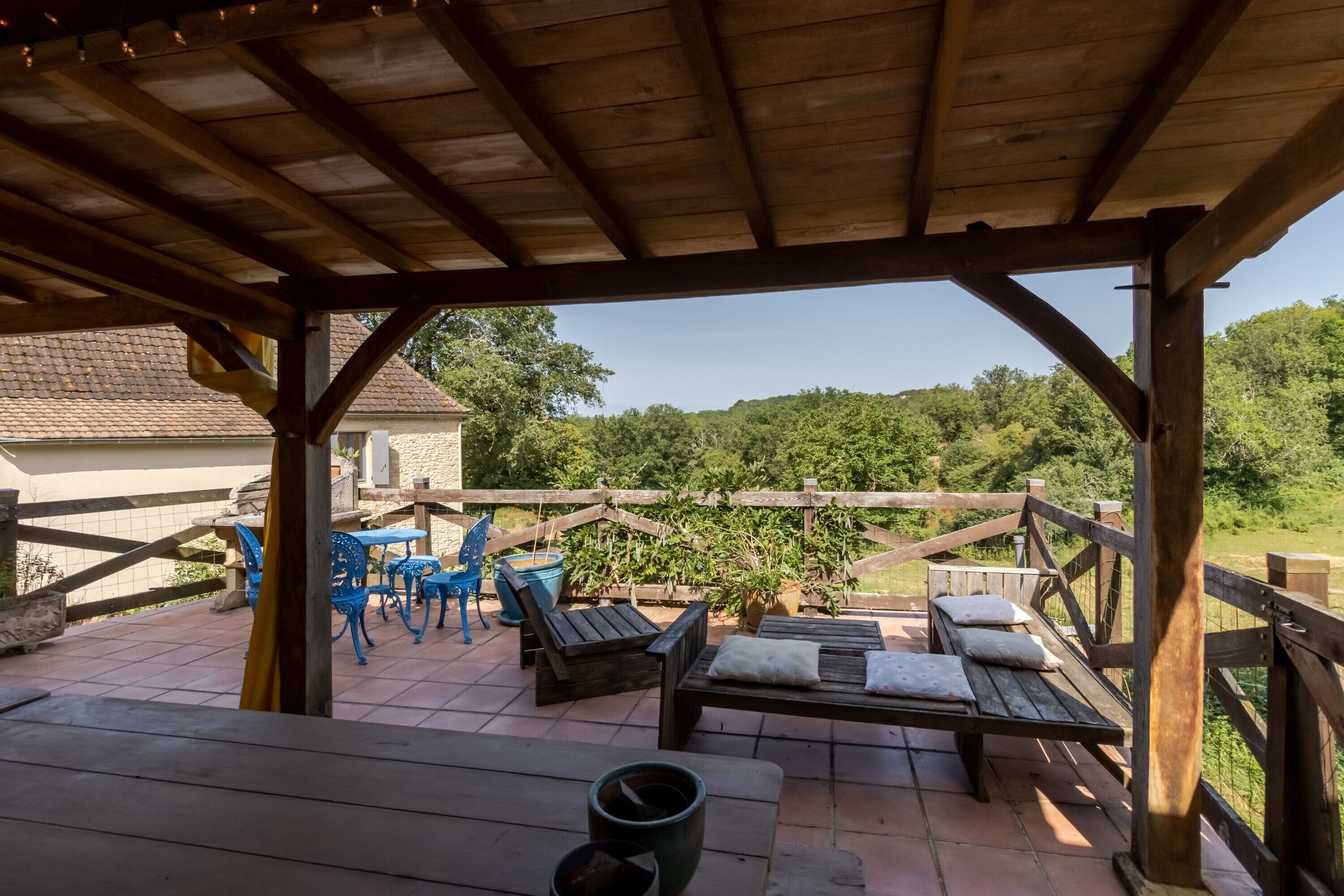 An outdoor patio with wooden furniture, a table, and chairs.