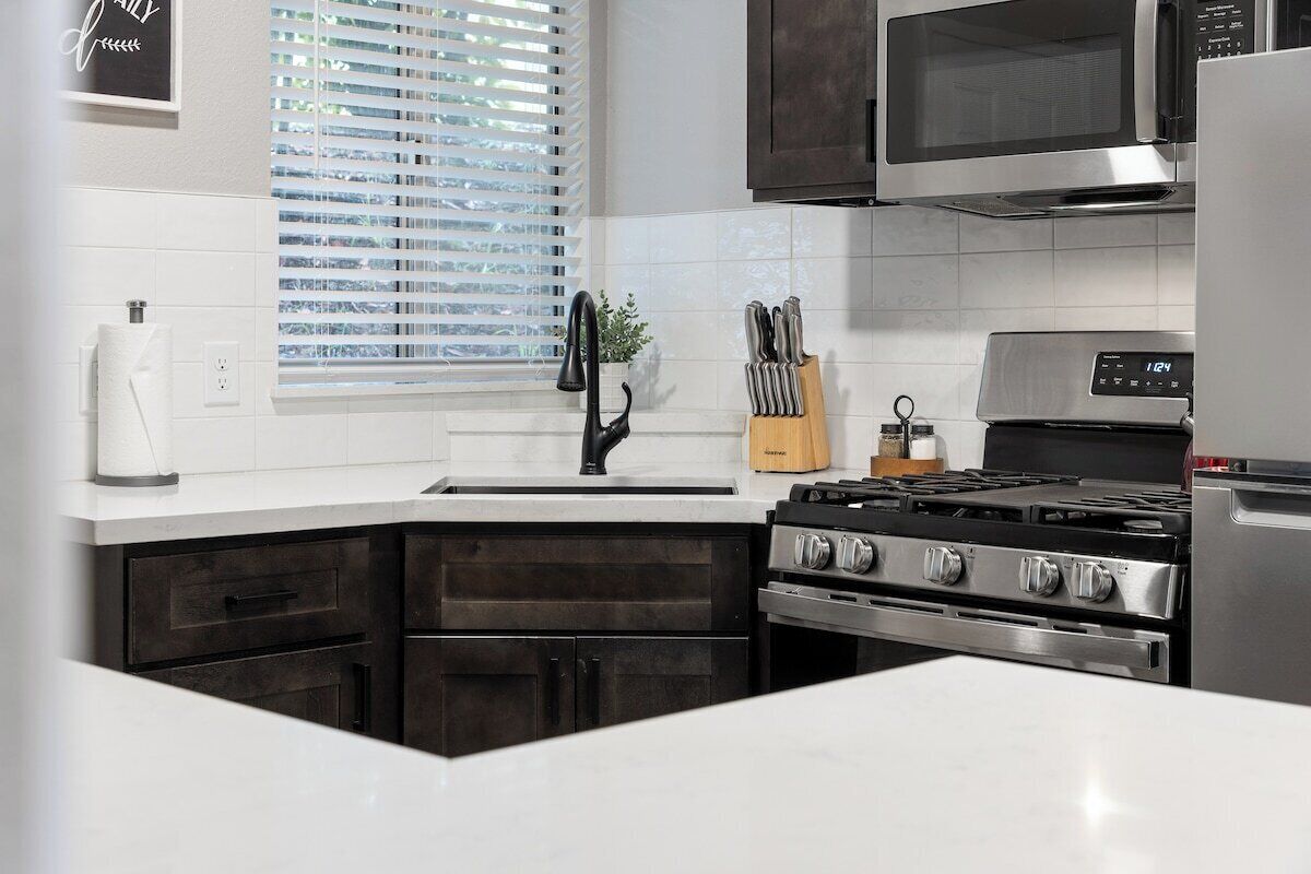 A kitchen with a stainless steel stove, a microwave, and a refrigerator.