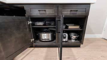 A kitchen with a dark cabinet, a toaster, a slow cooker, and a coffee maker on the countertop.