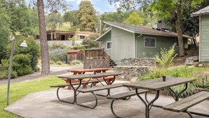 A picnic table set on a concrete patio with a stone wall and a wooden deck in the background. - The General Sherman Cabin Sequoia Motel (Three Rivers)