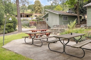 A picnic table set on a concrete patio with a stone wall and a wooden deck in the background.