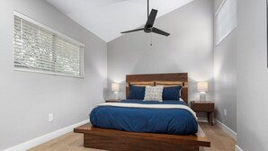 A bedroom with a bed, ceiling fan, bedside lamps, and a window with blinds. - The General Sherman Cabin Sequoia Motel (Three Rivers)